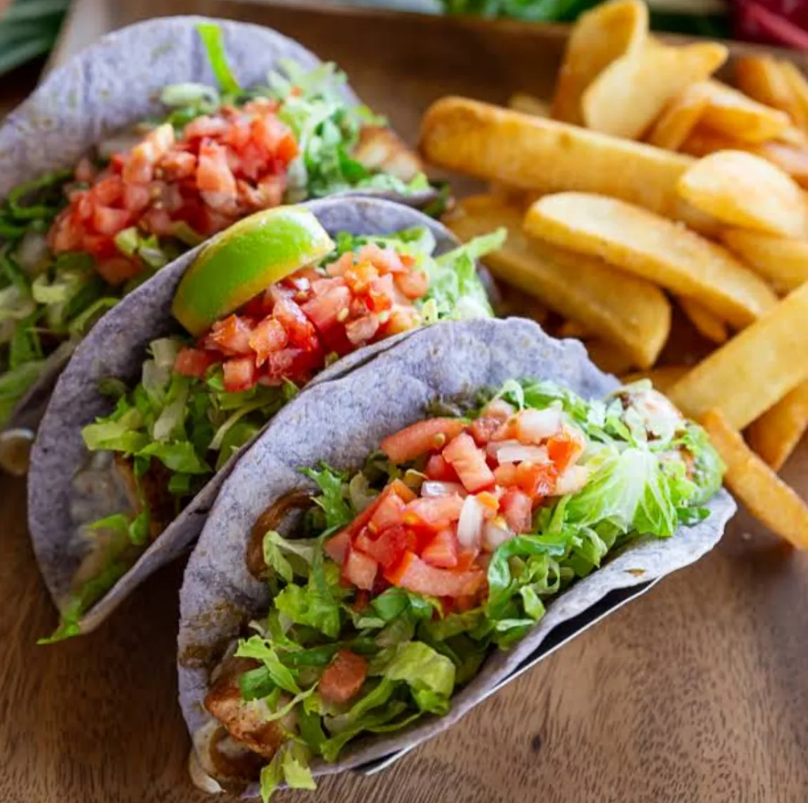 Image: Family sharing plate lunches—kalua pork, rice, mac salad—at a shaded picnic table
