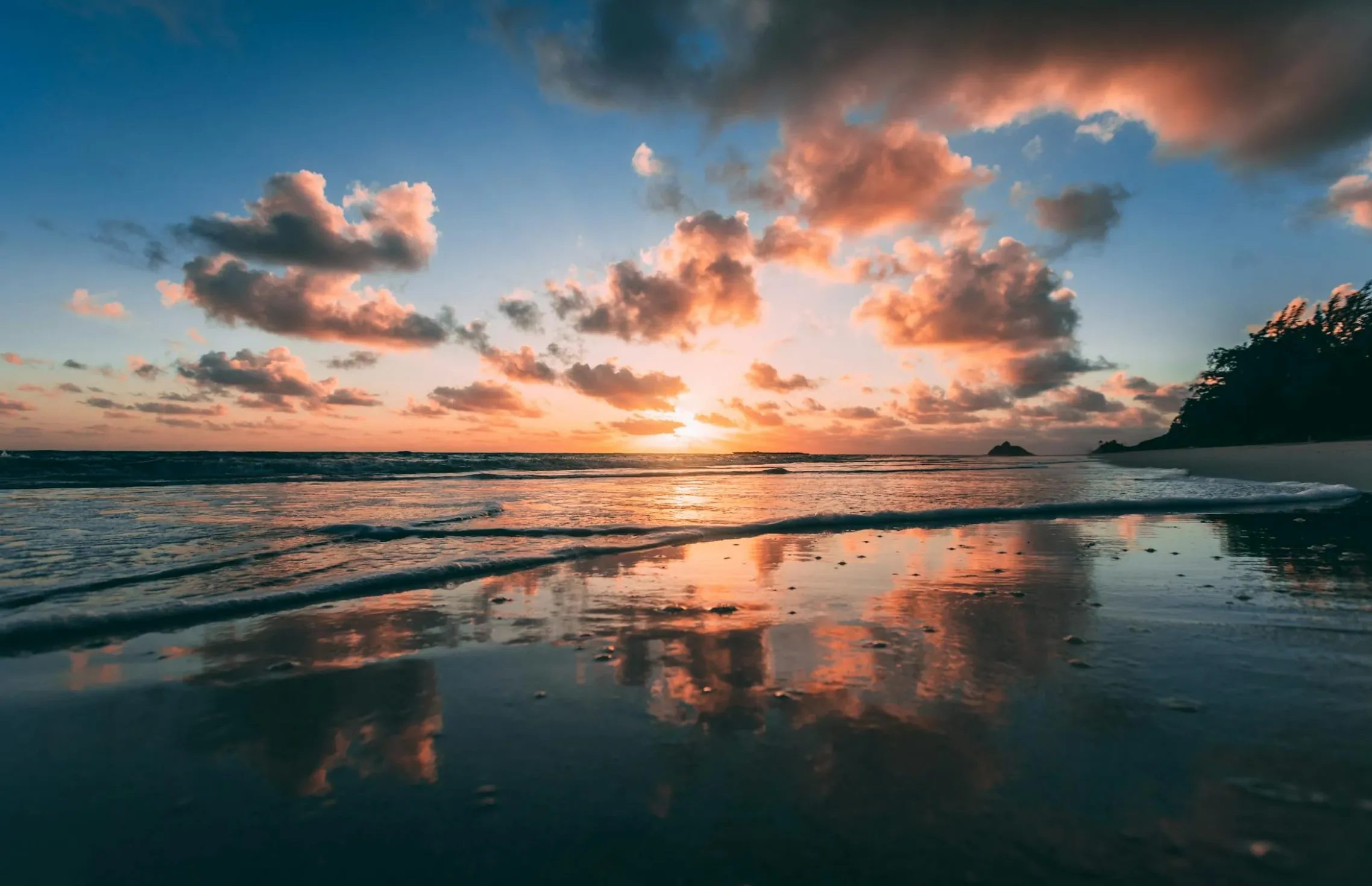 Image: Teens paddling a tandem kayak over clear turquoise water off Lanikai with the Mokulua islets ahead